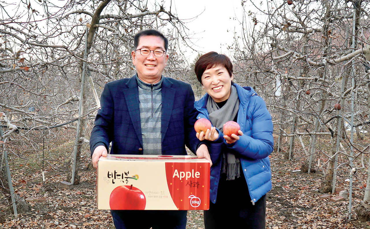 무주군에서 사과농사를 짓는 김성곤 한농연무주군연합회장이 아내 김옥순씨와 함께 직접 재배한 사과를 들고 밝게 미소 짓고 있다.