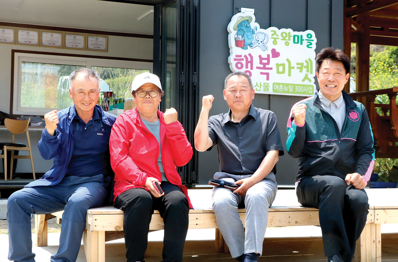 박현규 중왕어촌계장(오른쪽 두 번째)과 어촌계원들이 자체적으로 운영하고 있는 카페를 배경으로 파이팅을 외치고 있다.